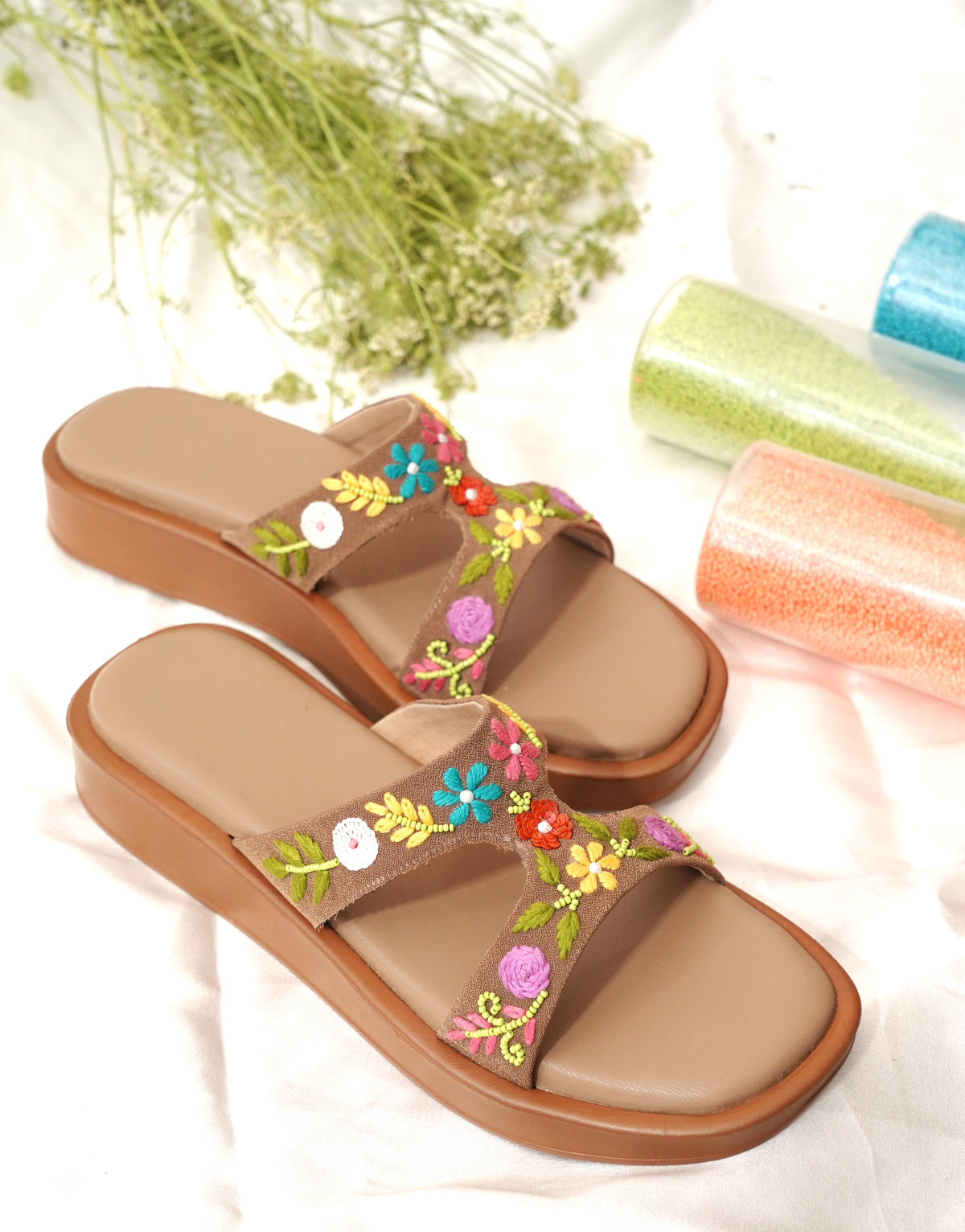 Sydney Brown Flatforms angled pair flat lay by Solemates by Palak — brown flatform sandal with multicolour floral hand embroidery and bead vine detailing, styled with dried botanicals and coloured beads