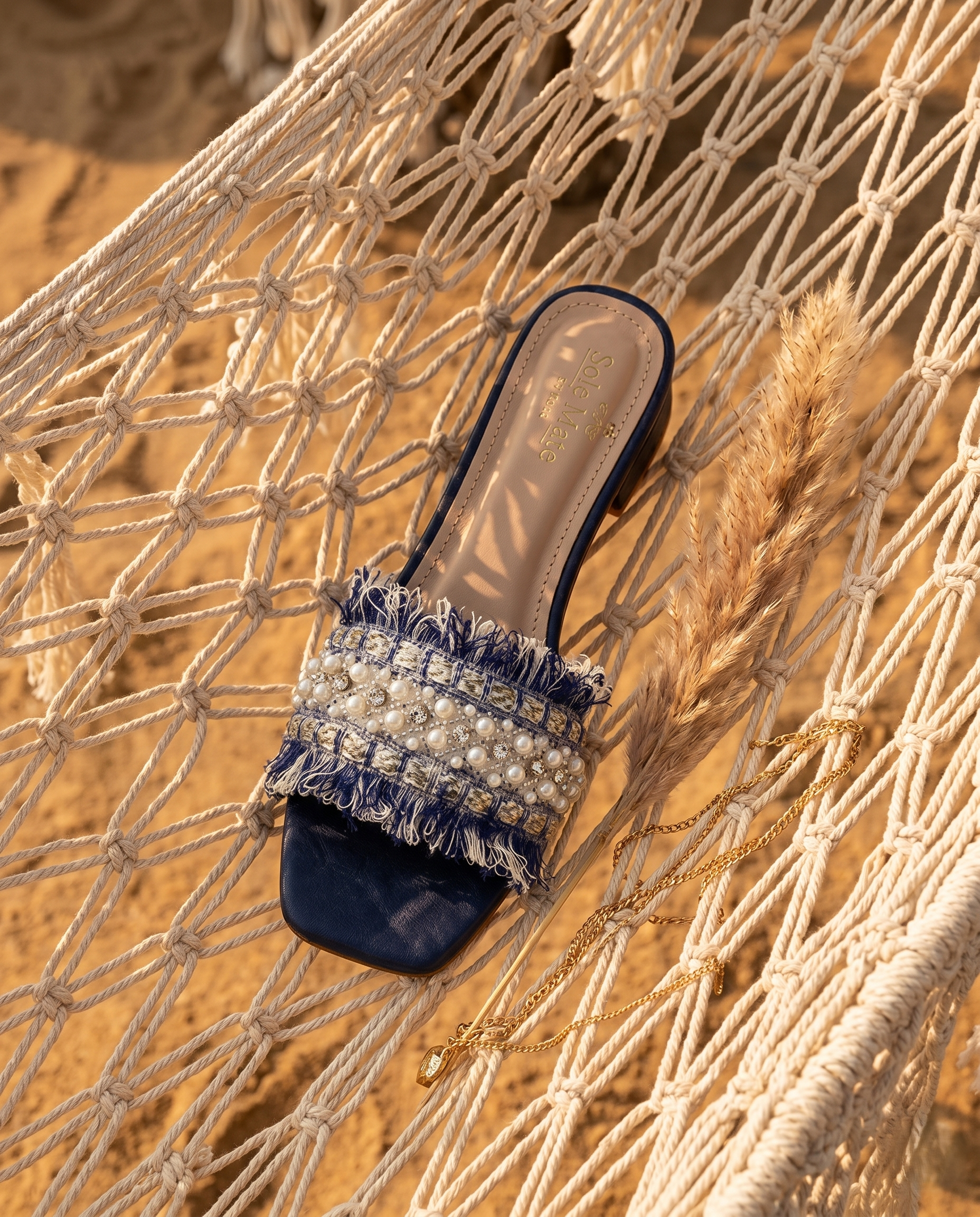Boho Chic Blue slider by Solemates by Palak on macramé net flat lay — navy tweed fringe strap with pearl and crystal embellishment, tan insole visible