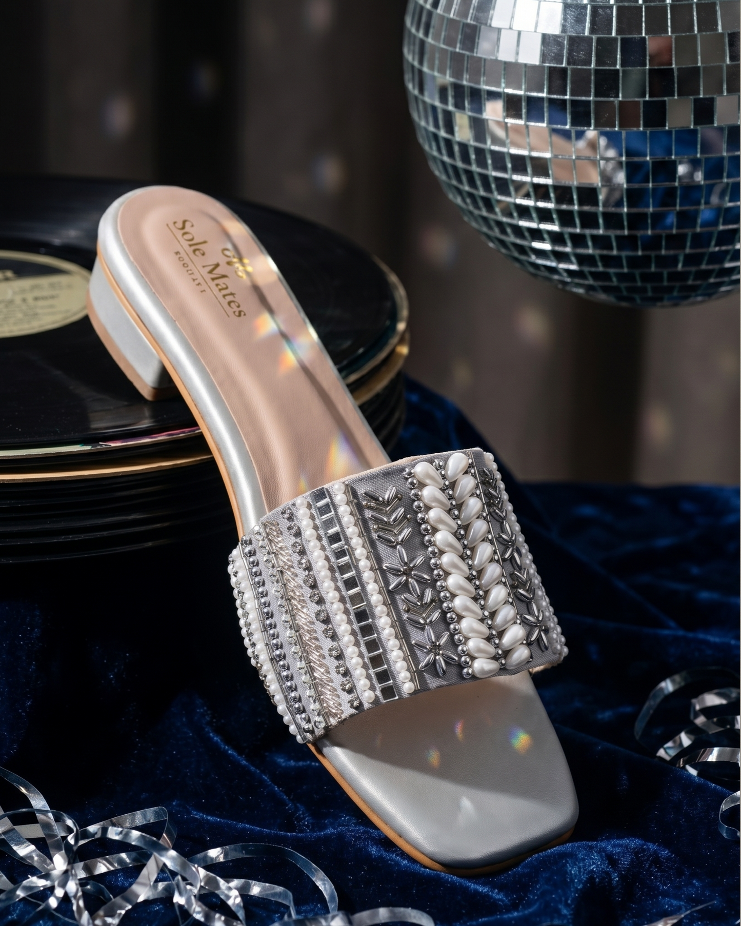 Kate Silver Sliders on vinyl records against disco ball and blue velvet — wide shimmer strap with teardrop pearl clusters and silver bead work by Solemates by Palak