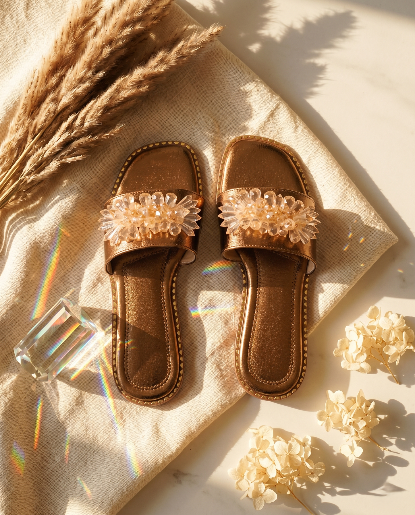 Copper Mirage slider pair top-down flat lay — copper metallic pebbled upper with 3D crystal floral embellishment and gold stud sole trim by Solemates by Palak