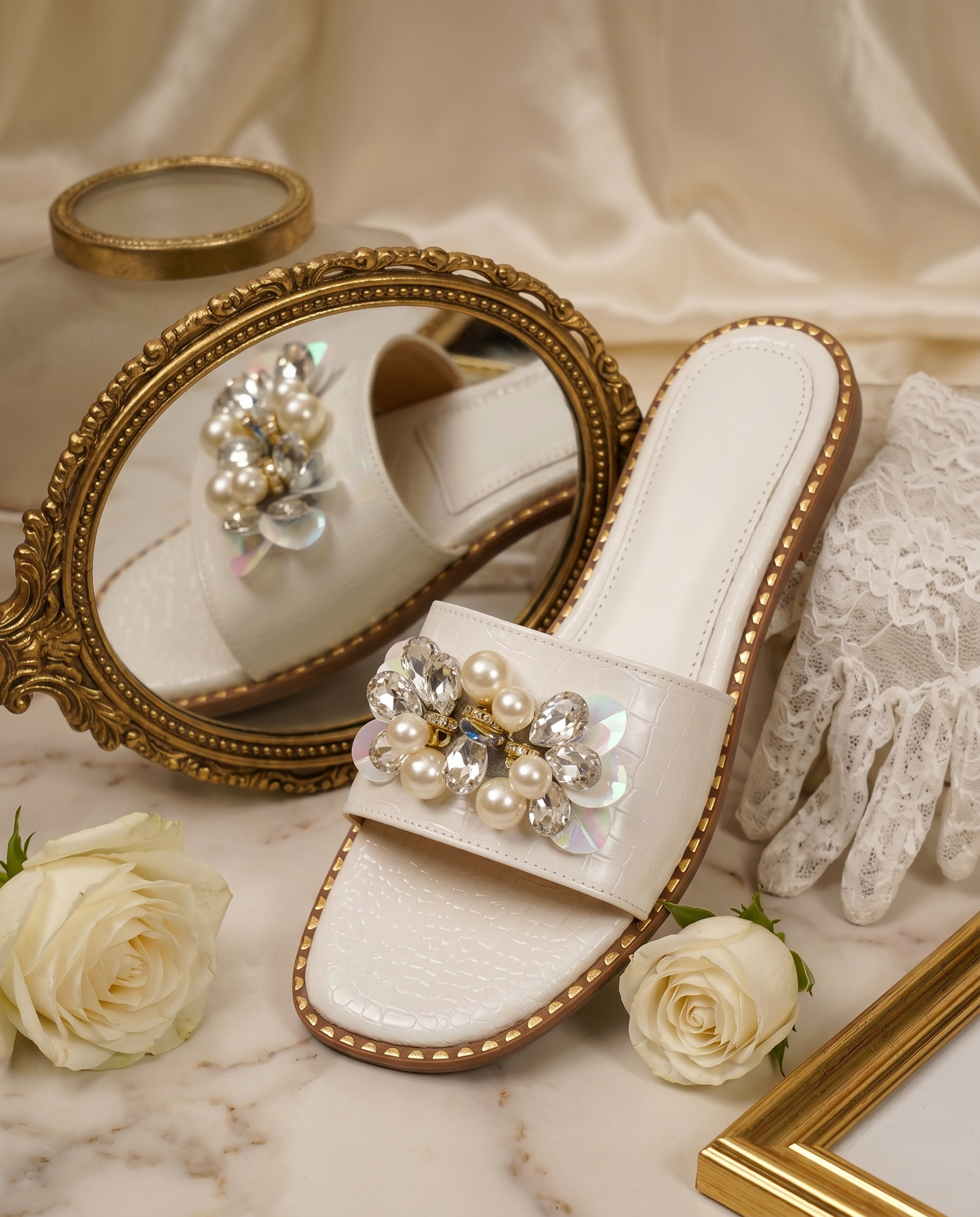 Topaz White embellished ivory croc-textured slider by Solemates by Palak — flat lay with gold mirror and white roses
