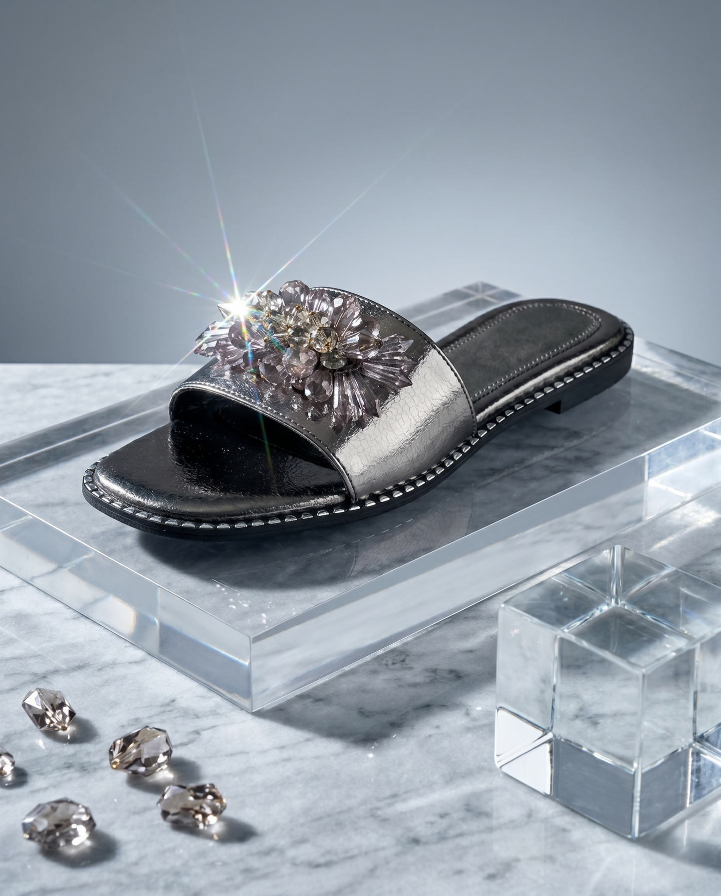 Grey Mirage Flat Sliders on acrylic block with light flare — gunmetal metallic flat slider with 3D crystal floral brooch embellishment by Solemates by Palak